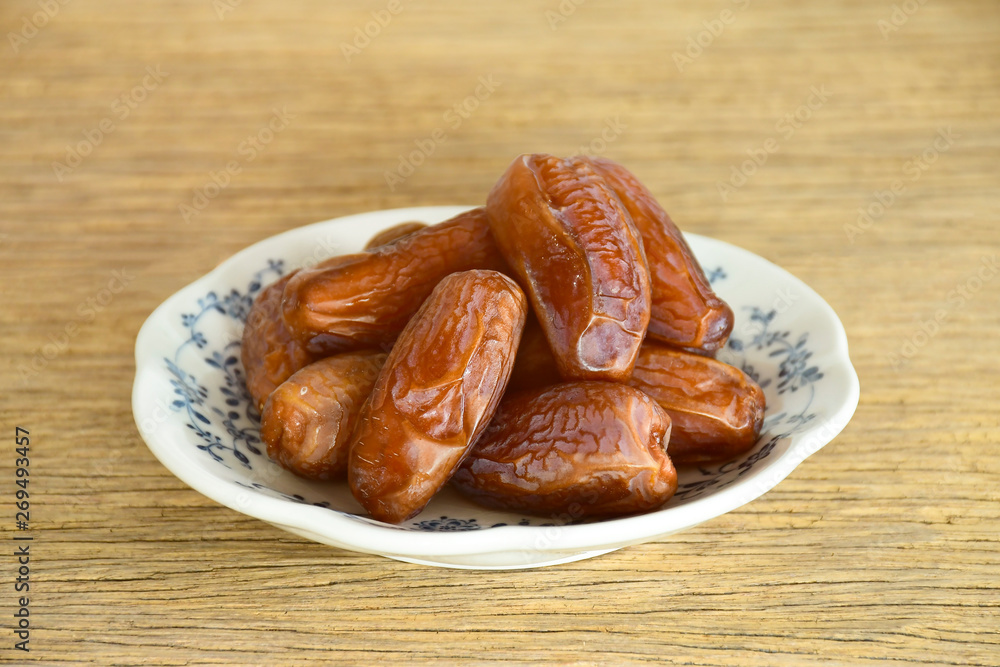 Wall mural dried dates fruit in ceramic dish on old wood table.