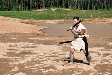 Concept photo of a Roman warrior of the Colosseum in action with aggressive emotions in full military uniforms on a desert landscape on a sunny day with a dry sun.
