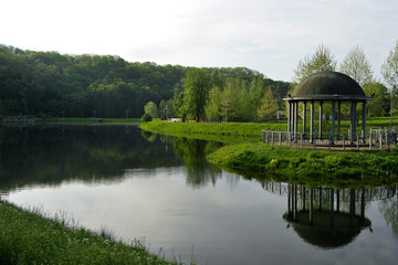 Fototapeta na wymiar Romantic gazebo on the lake in a large beautiful park.