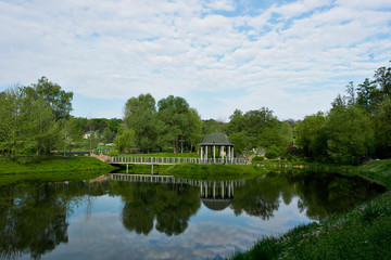 Fototapeta na wymiar Romantic gazebo on the lake in a large beautiful park.