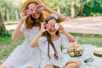 Stylish young woman came with pretty daughter to park to spend weekend together. Outdoor portrait...