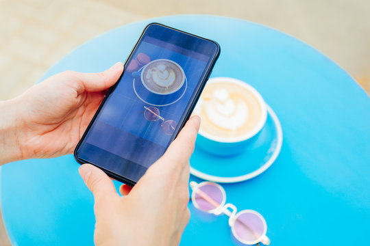 Picture of a coffee on a smartphone on a blue table.