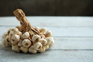 Many garlic that binds together into a bunch on white wooden floor