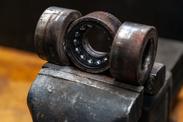 A close-up of a metal car spare part bearing from a supported car on a metal table in a car repair shop