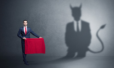 Businessman standing with red cloth in his hand and devil shadow on the background
