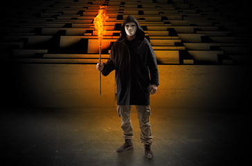 Ugly, aberrant man coming out from the labyrinth with burning flambeau on his hand
