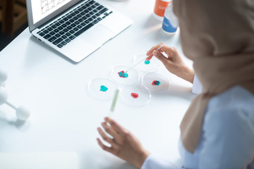 Female chemist wearing hijab analyzing chemical agents