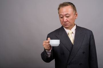 Portrait of mature Asian businessman against gray background