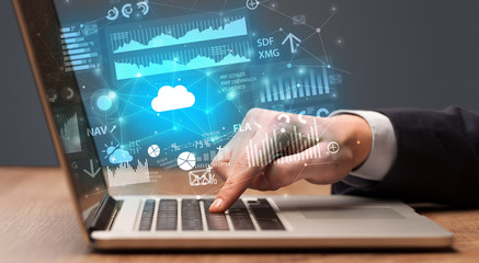 Businessman hand typing on laptop with reports and graphs concept around
