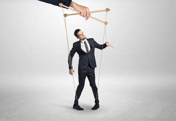 Puppet businessman in an empty room leaded by a huge hand
