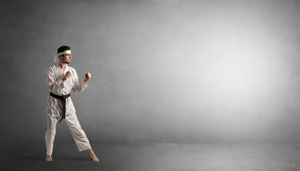 Small karate man fighting in an empty grey copy space