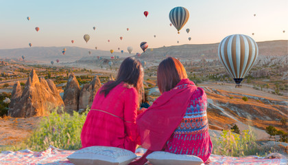 Hot air balloon flying over spectacular Cappadocia - Girls watching hot air balloon at the hill of Cappadocia