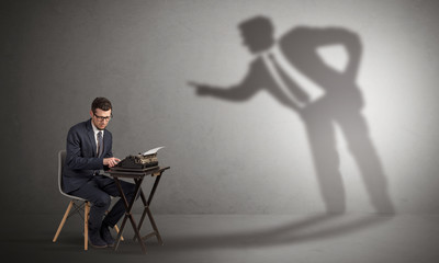 Little man working and a big shadow arguing with him
