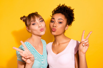 Close up photo beautiful she her lady hold hands arms show v-sign send air kisses buddies fellows different nationalities  wear casual white striped t-shirt clothes isolated yellow bright background