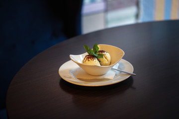 Ice cream balls in a white bowl in a cafe, dark