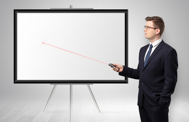 Young businessman with laser pointer and copyspace white wall
