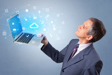 Man holding laptop projecting notifications, symbols and information based on cloud technology system
