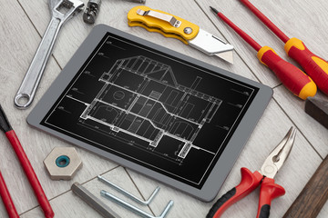Tablet with construction tools and blueprint concept
