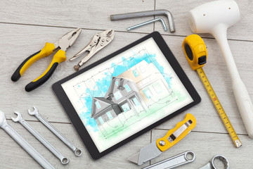 Tablet with construction tools and house plan concept
