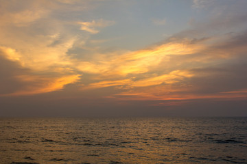 Naklejka na ściany i meble ocean under purple sunset sky with bright orange clouds