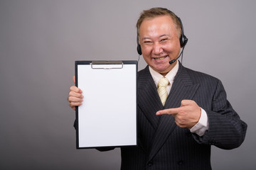 Portrait of mature Asian businessman against gray background
