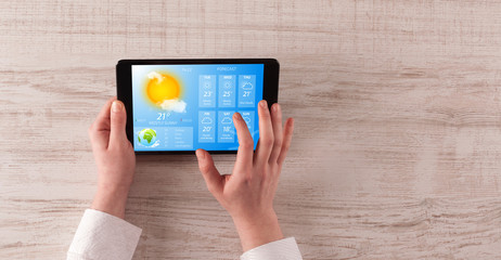 Man hand checking weekly weather forecast on tablet
