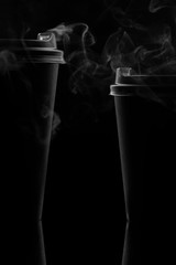 Two paper disposable black cups on a black background are shrouded in steam. - 269507094
