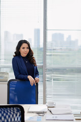 Portrait of Asian young businesswoman standing near the table and looking at camera during business meeting at office