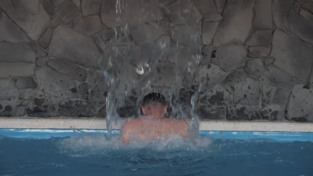 Man doing a back massage. Hydrotherapeutic procedure. Healthy back. Concept: Spa treatments, body massage, swimming pool. Clean, blue water in the pool. Slow motion video.