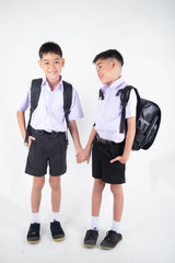 Little Asian sibling boys in student uniform pose together on white background