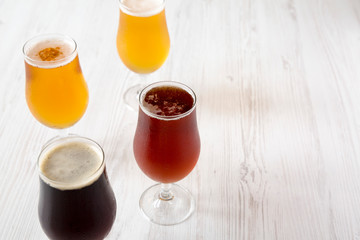 Assorted cold craft beer on a white wooden background, side view. Copy space.