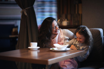 Mom and daughter communicate, hug and kiss in cafe