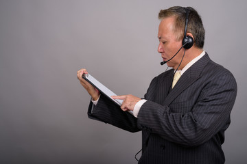 Portrait of mature Asian businessman against gray background