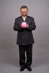 Portrait of mature Asian businessman against gray background