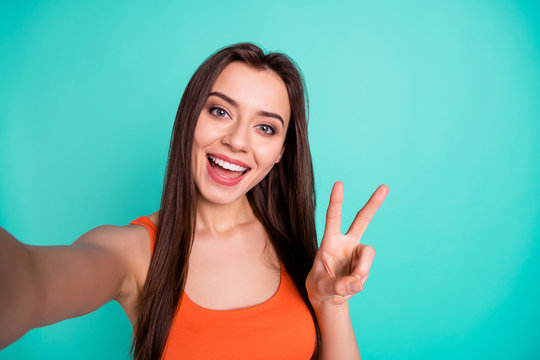 Close up photo beautiful amazing her she lady coquette make take selfies v-sign symbol hand arm tell speak say skype toothy wear casual orange tank-top isolated bright blue teal turquoise background