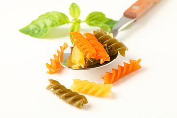 Spoon with color pasta on white background, space for text and closeup