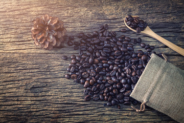 Coffee bean in spoon and bag on wood background