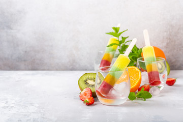 Delicious homemade popsicle with different flavors, mango, orange, kiwi and strawberry in glass...
