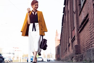 Happy young business woman walking on the street.