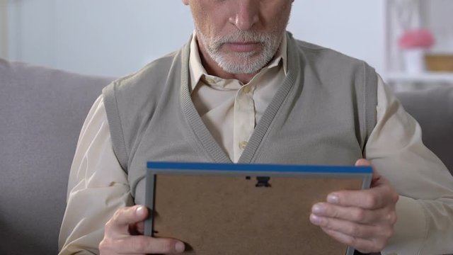 Upset senior widower hugging photo, missing and remembering wife, depression