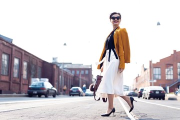 Happy young business woman walking on the street.