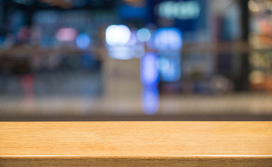 Empty wood table top and blur of shopping mall background.