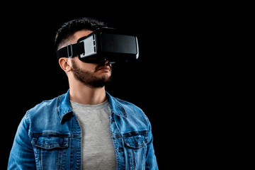 Portrait of a man in virtual reality glasses, vr, against a dark background. The concept of the future is here, applications complement reality, the virtual reality interface. Copy space.