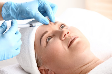 Mature woman receiving filler injection in beauty salon