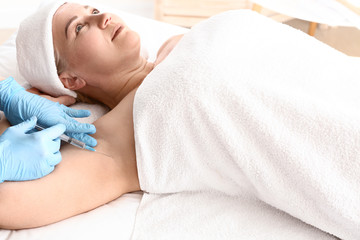 Obraz na płótnie Canvas Woman receiving botox injection in armpit as treatment of hyperhidrosis in beauty salon
