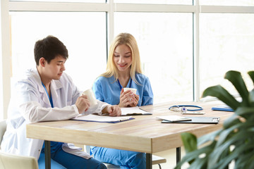 Male doctor and female medical assistant drinking coffee during break in clinic