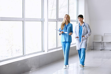 Male doctor and female medical assistant walking down the corridor in clinic