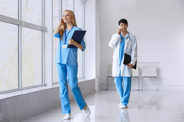 Male doctor and female medical assistant walking down the corridor in clinic