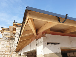 close up view of scaffolding and house under construction with holders for gutters water drainage system