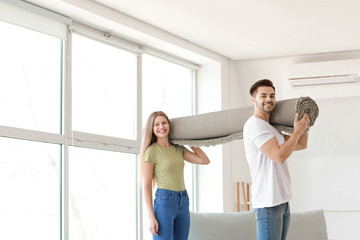 Fototapeta premium Young couple with carpet in new flat